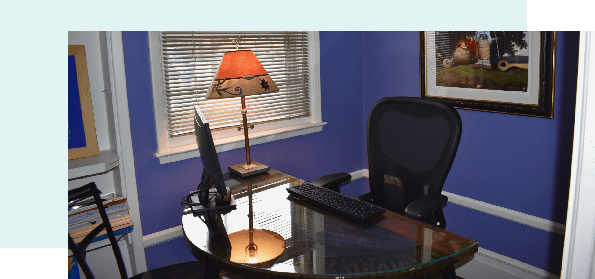 An office with purple walls and a desk, chair and computer